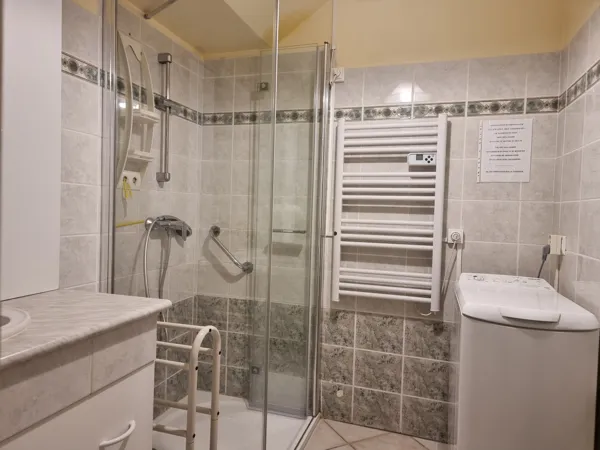 Salle de bain avec vasque, douche, lave linge et radiateur sèche serviettes