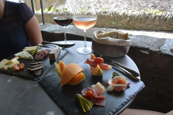 Profitez d'un moment à Conques pour aller boire une verre de vin et manger un plateau de charcuterie sous une terrasse ombragée