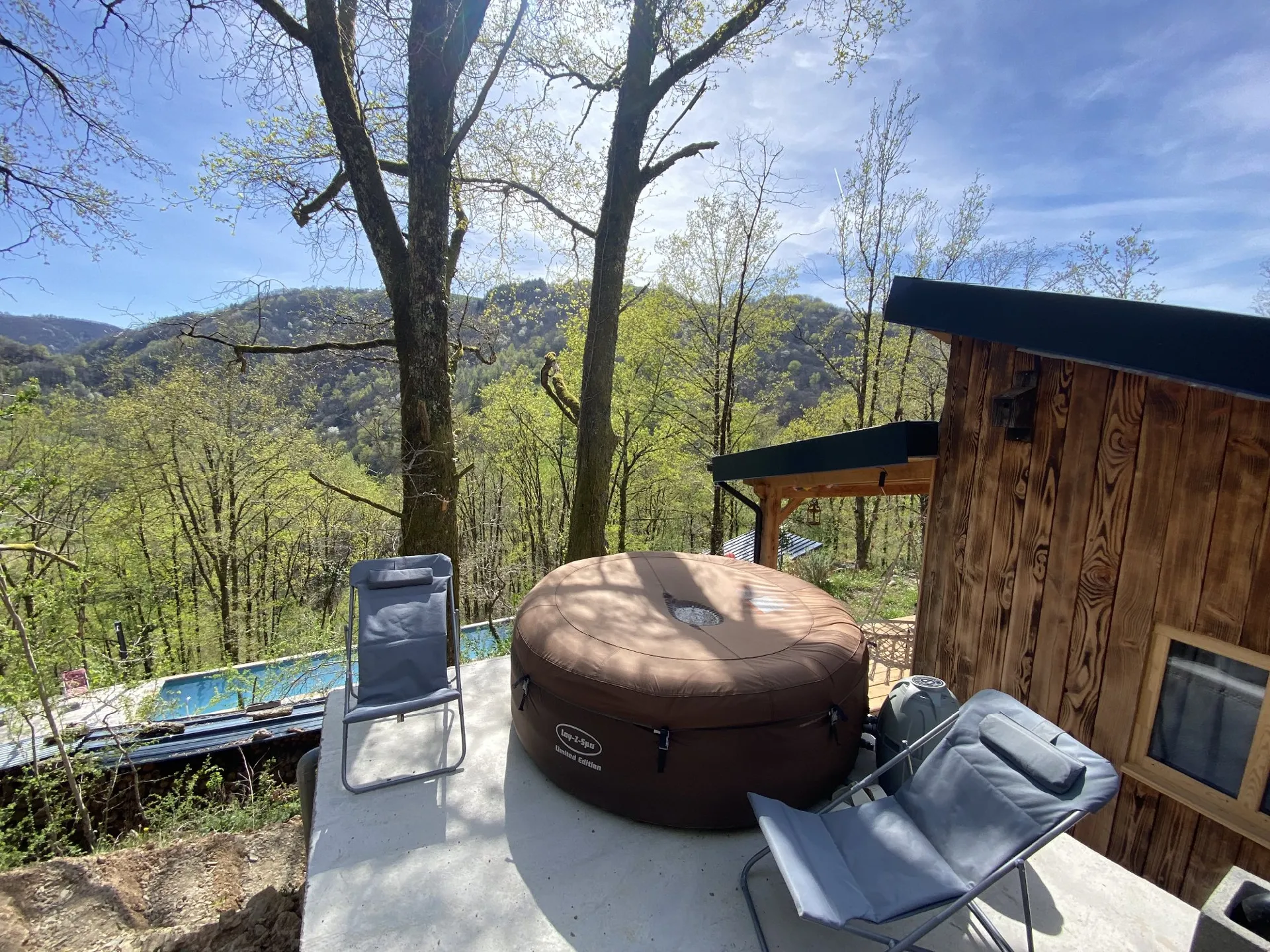 Vue du jacuzzi sous les grands chênes surplombant la maison et le jardin. Vue sur la vallée.